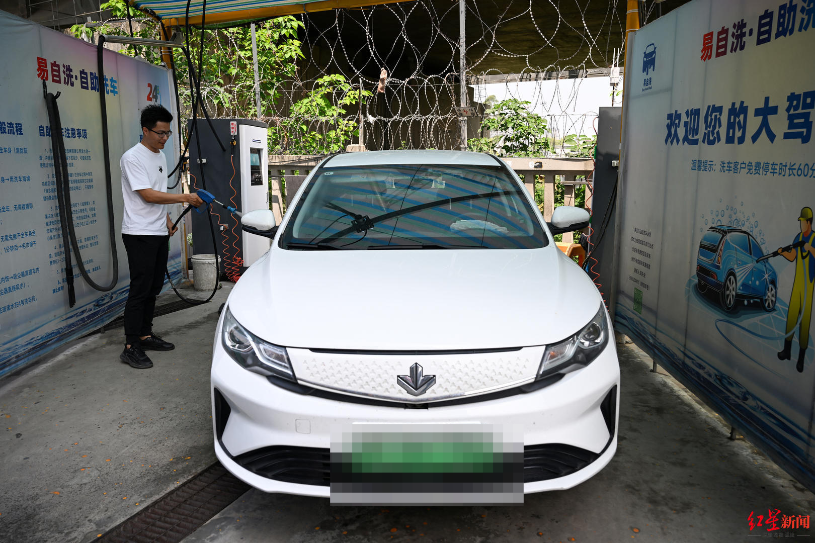 ▲网约车司机张洁正在洗车
